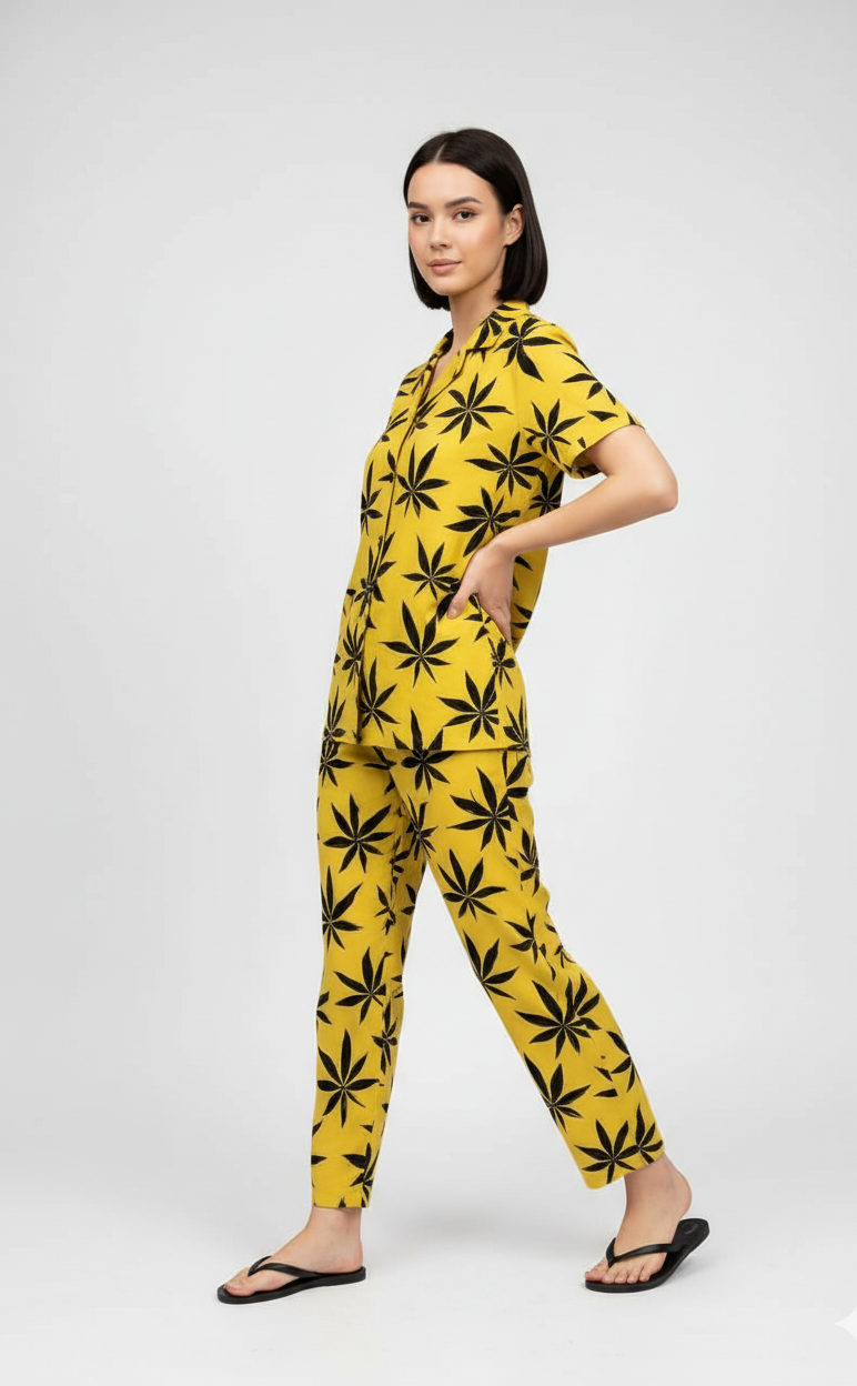 Woman wearing a yellow jumpsuit with black leaf pattern on a white background