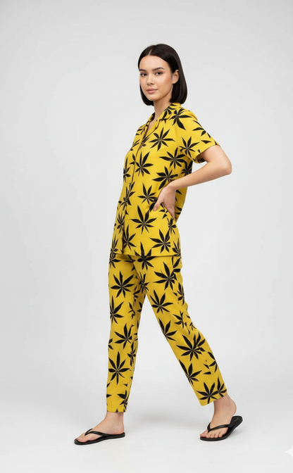 Woman wearing a yellow jumpsuit with black leaf pattern on a white background